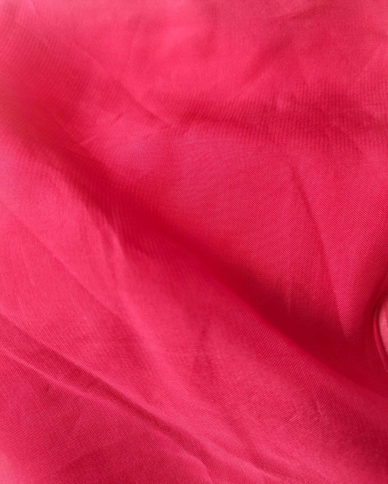 Close-up of soft, wrinkled pink cotton fabric displaying fine weave texture.