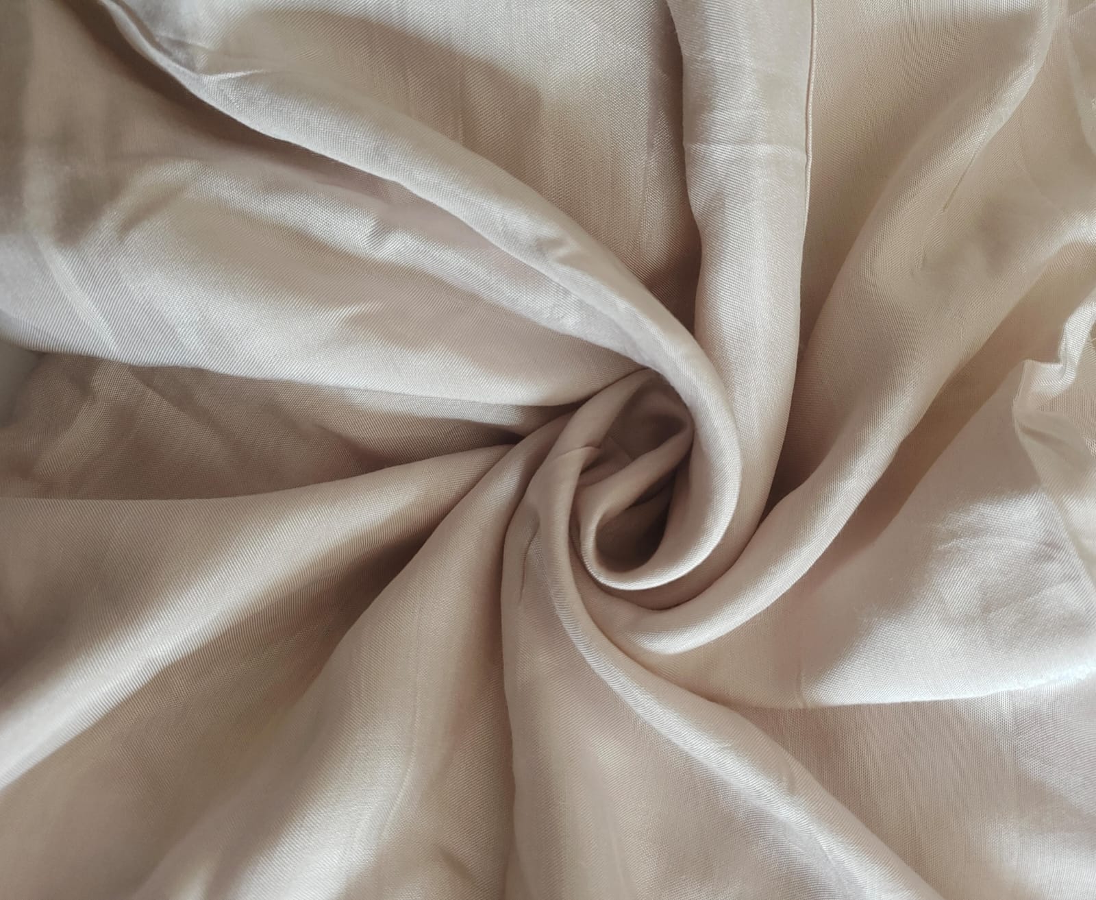 Close-up of soft, wrinkled pink cotton fabric displaying fine weave texture.