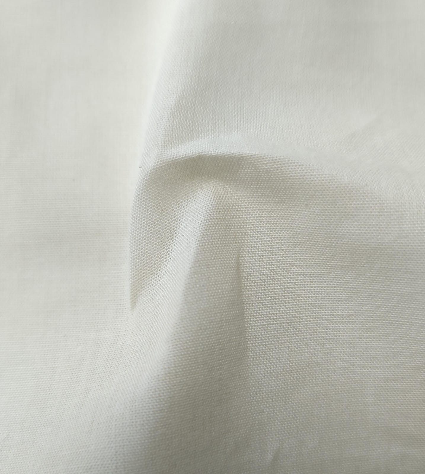Close-up of soft, wrinkled pink cotton fabric displaying fine weave texture.