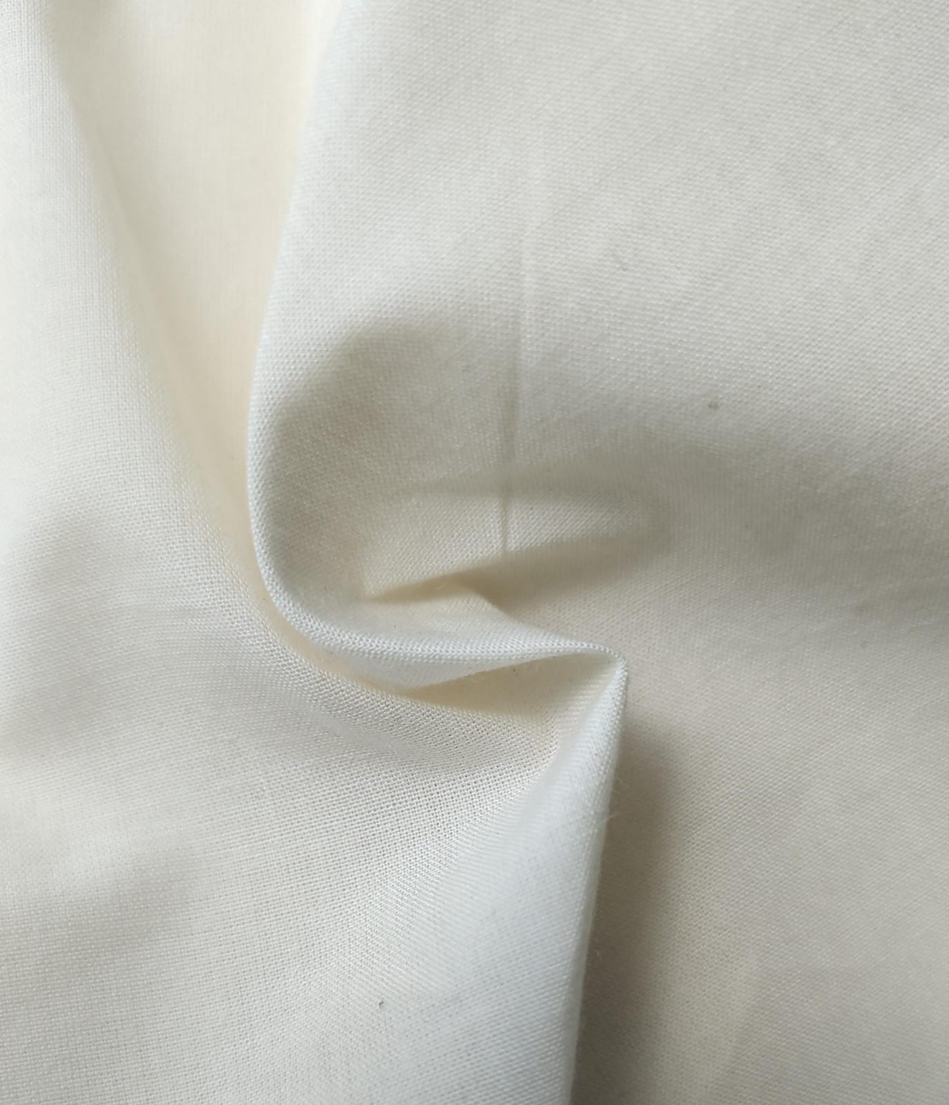 Close-up of soft, wrinkled pink cotton fabric displaying fine weave texture.