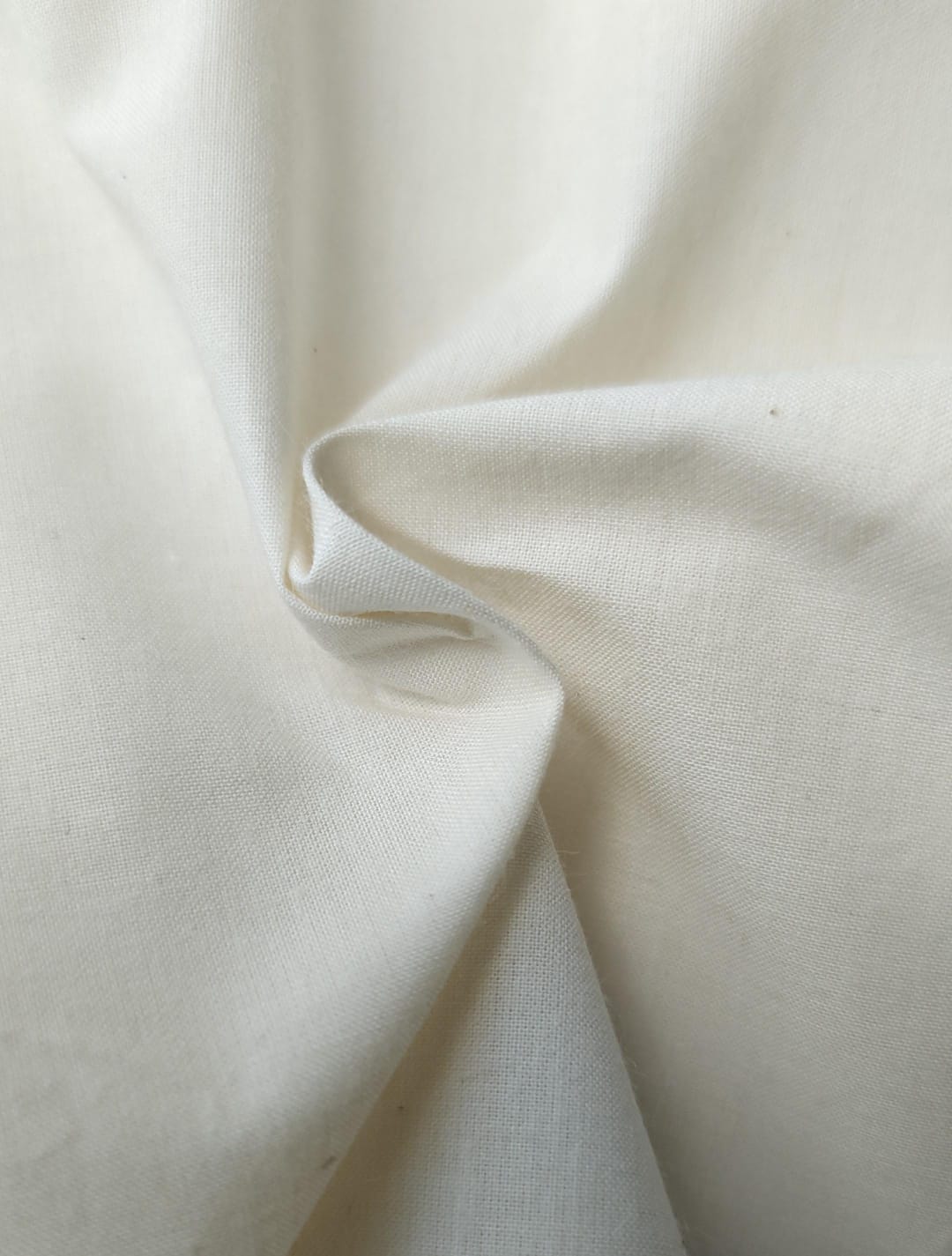 Close-up of soft, wrinkled pink cotton fabric displaying fine weave texture.