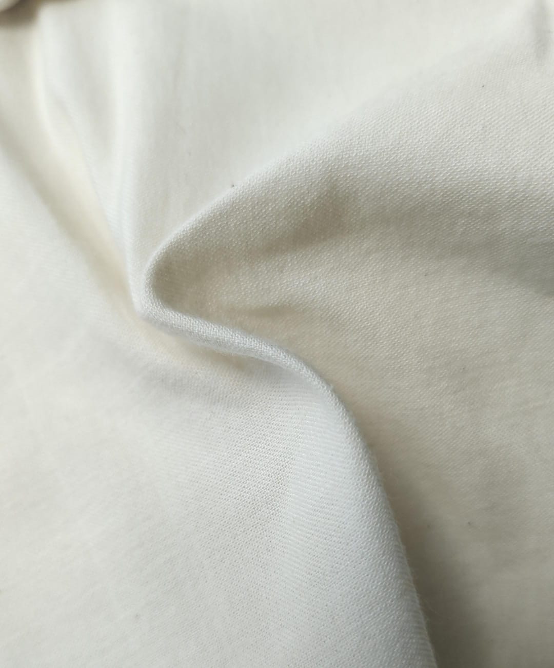Close-up of soft, wrinkled pink cotton fabric displaying fine weave texture.