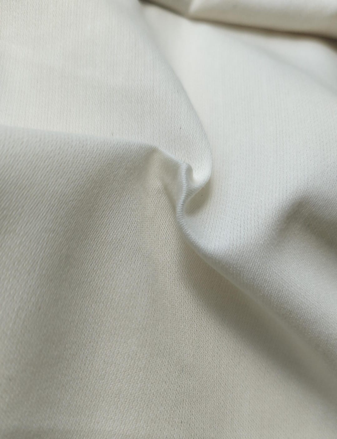 Close-up of soft, wrinkled pink cotton fabric displaying fine weave texture.