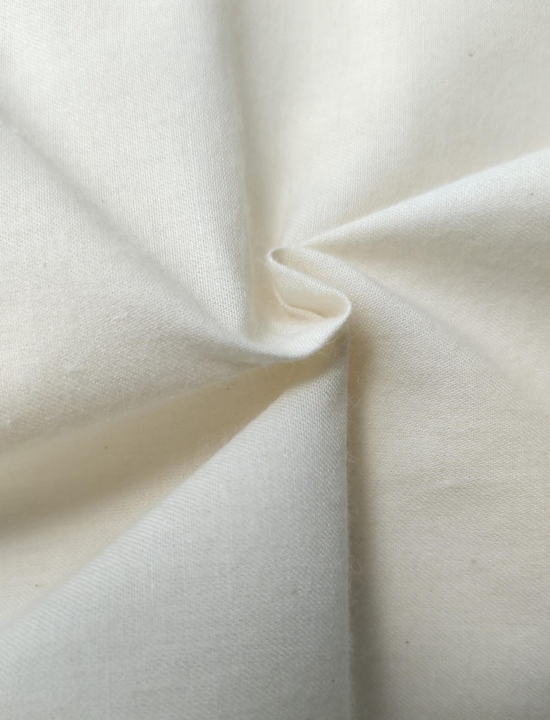 Close-up of soft, wrinkled pink cotton fabric displaying fine weave texture.