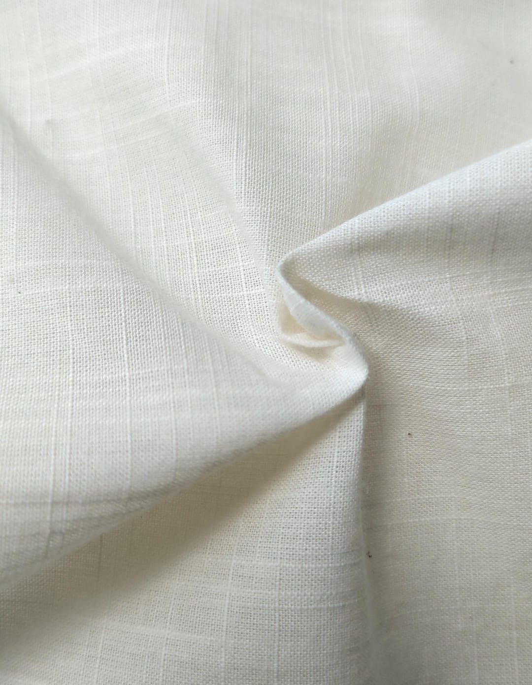 Close-up of soft, wrinkled pink cotton fabric displaying fine weave texture.