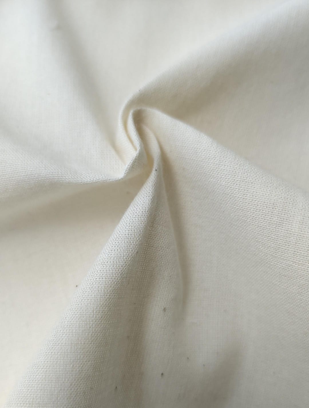 Close-up of soft, wrinkled pink cotton fabric displaying fine weave texture.