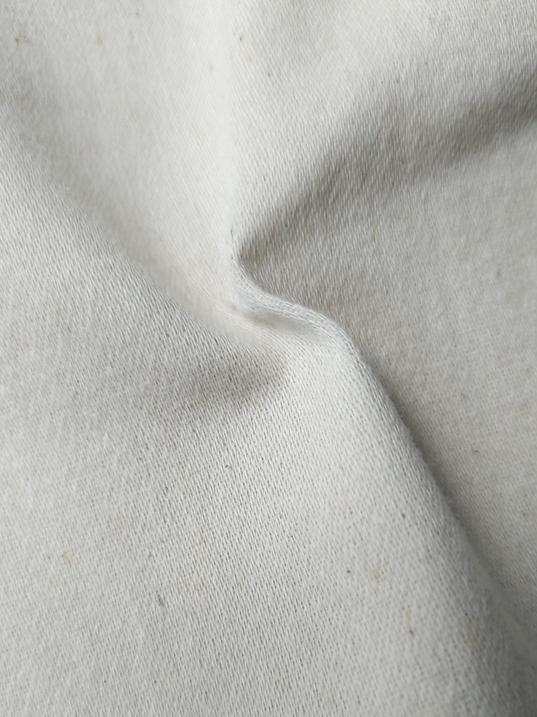 Close-up of soft, wrinkled pink cotton fabric displaying fine weave texture.