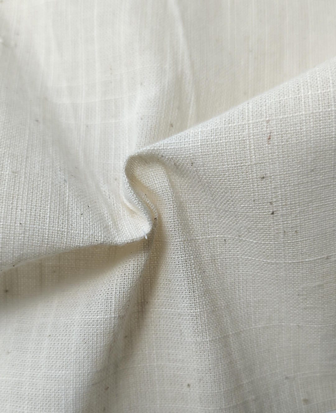 Close-up of soft, wrinkled pink cotton fabric displaying fine weave texture.