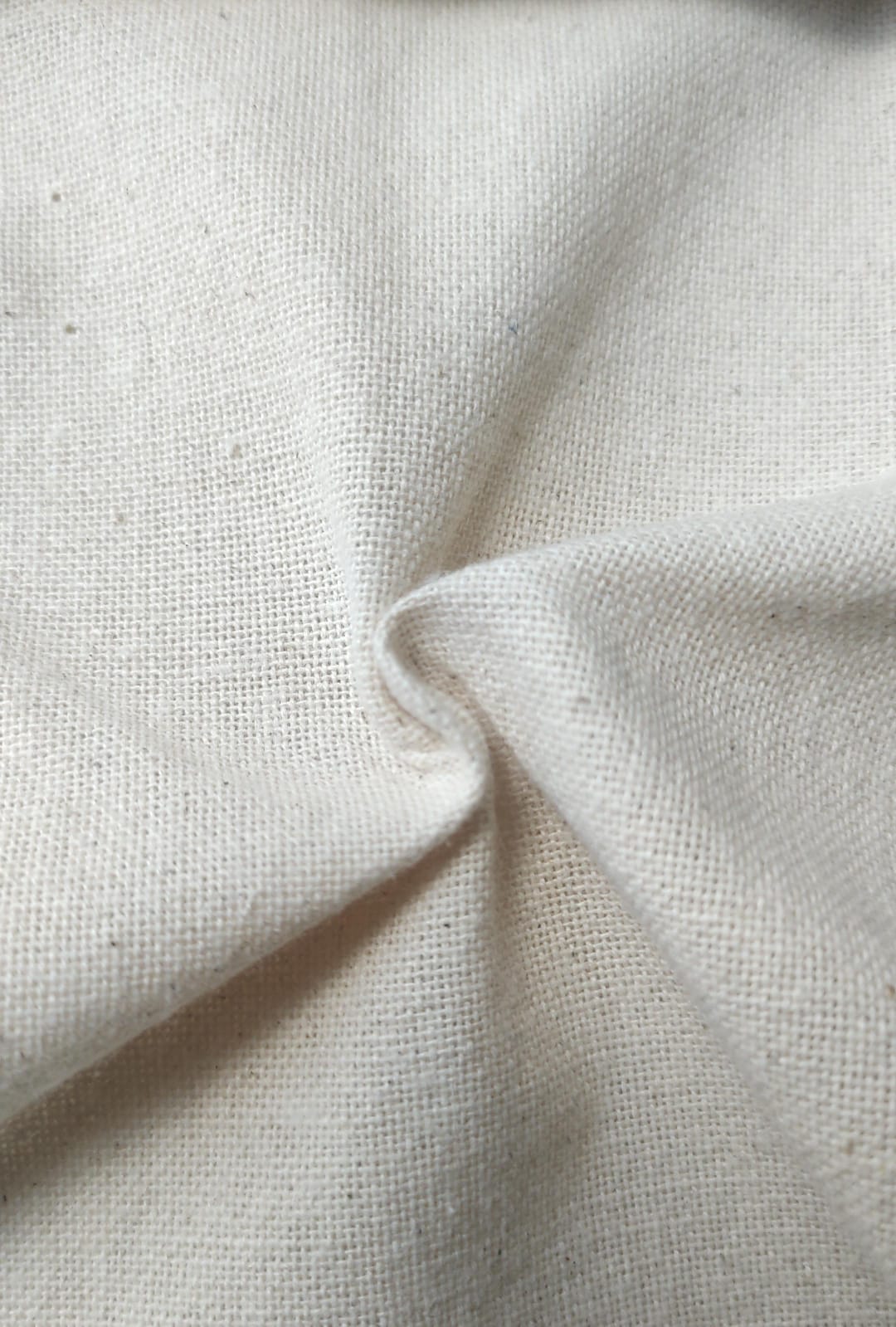 Close-up of soft, wrinkled pink cotton fabric displaying fine weave texture.