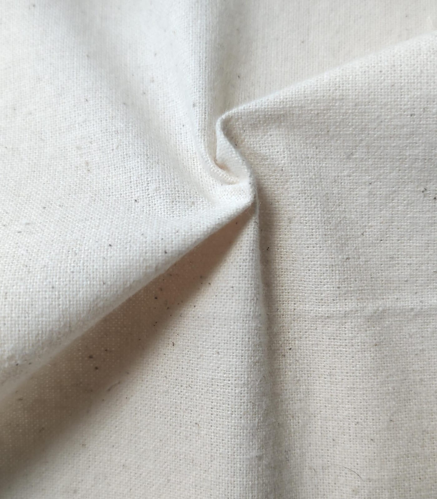 Close-up of soft, wrinkled pink cotton fabric displaying fine weave texture.