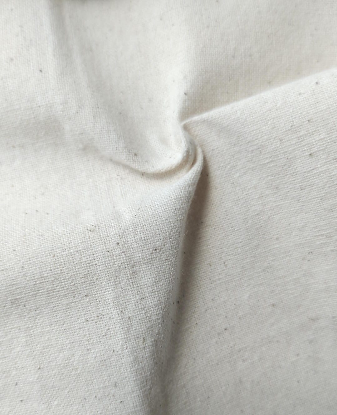 Close-up of soft, wrinkled pink cotton fabric displaying fine weave texture.