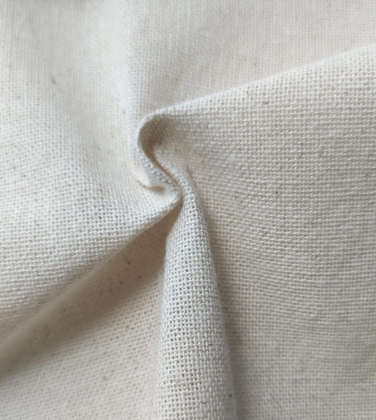 Close-up of soft, wrinkled pink cotton fabric displaying fine weave texture.