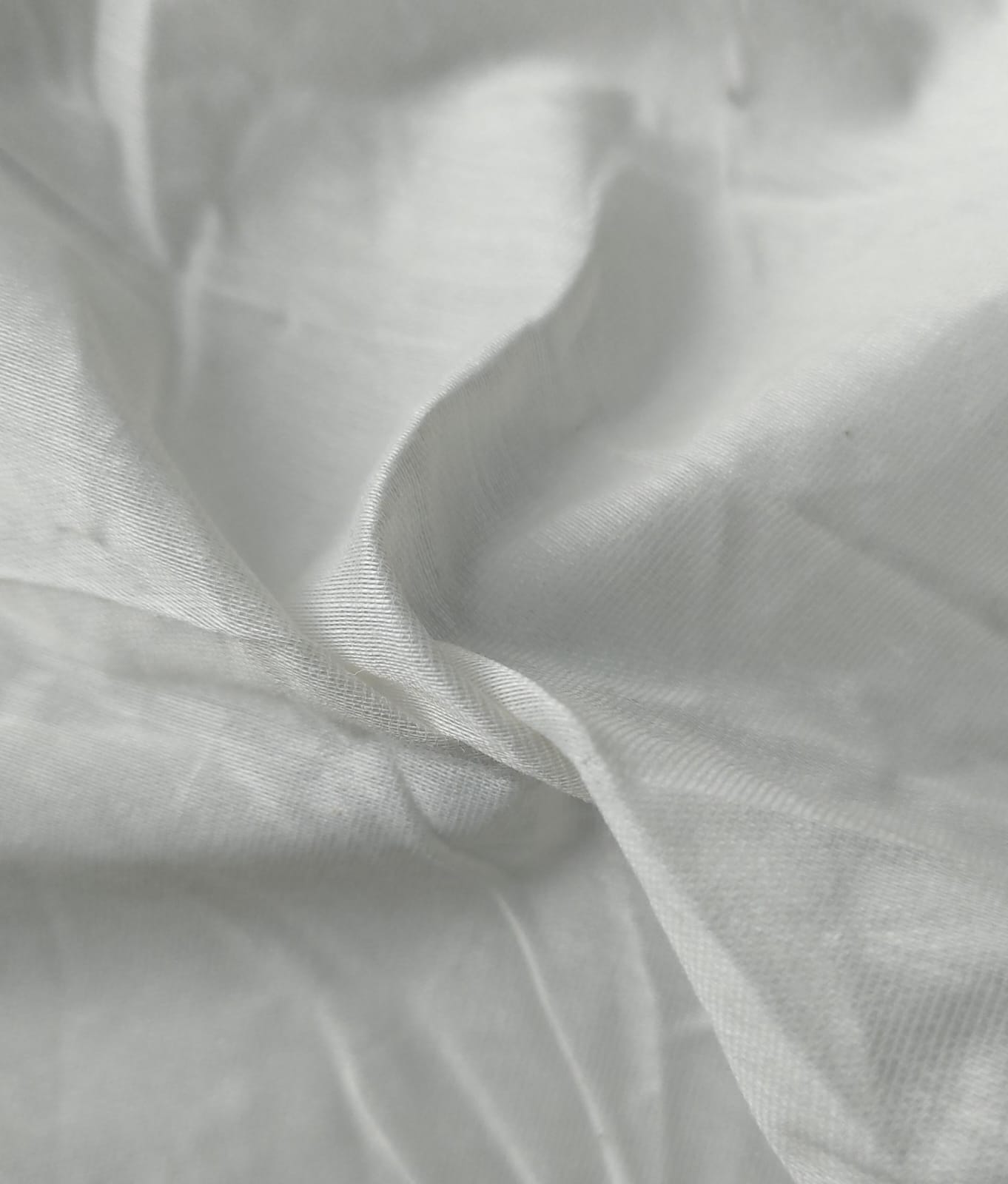 Close-up of soft, wrinkled pink cotton fabric displaying fine weave texture.