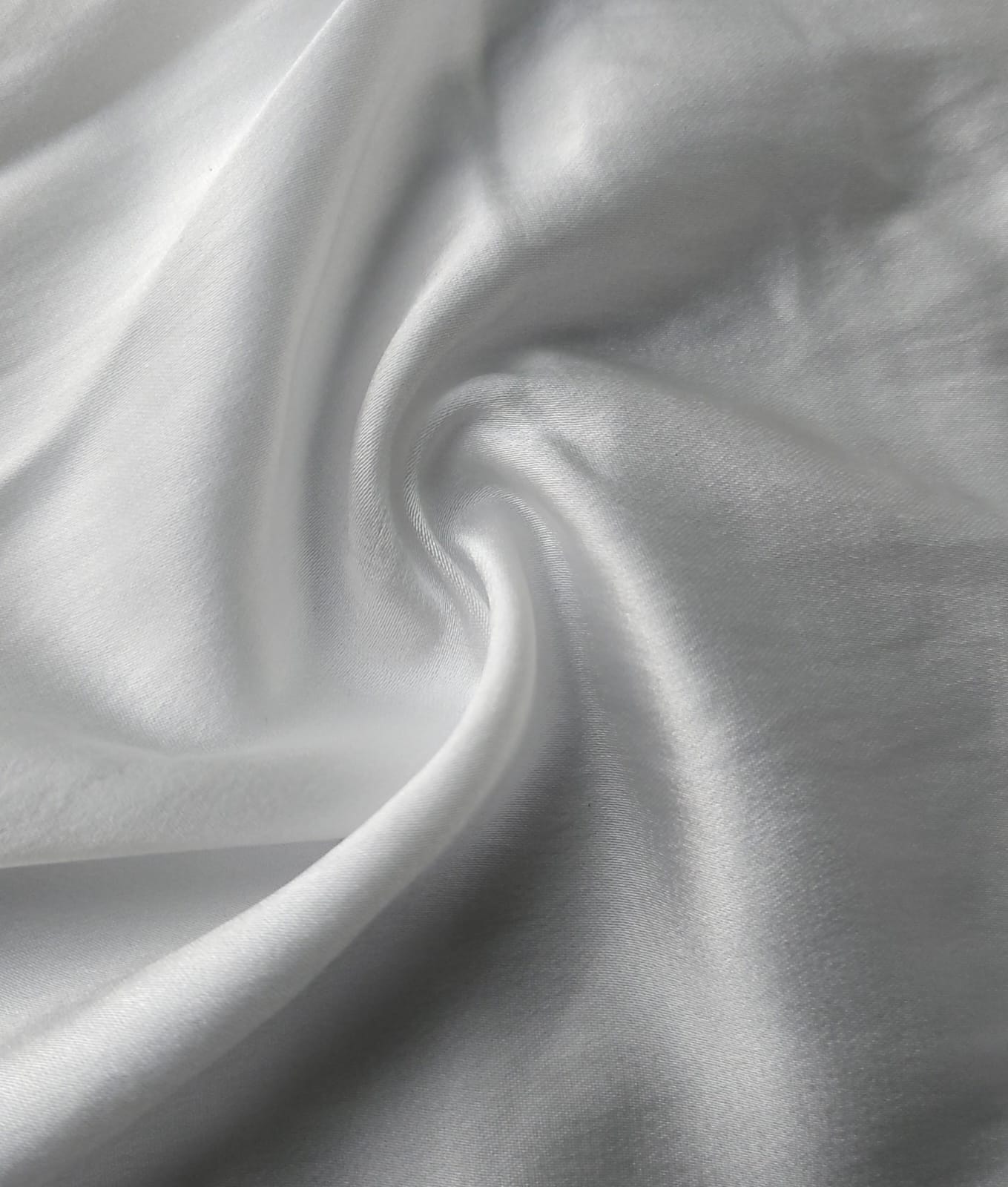 Close-up of soft, wrinkled pink cotton fabric displaying fine weave texture.