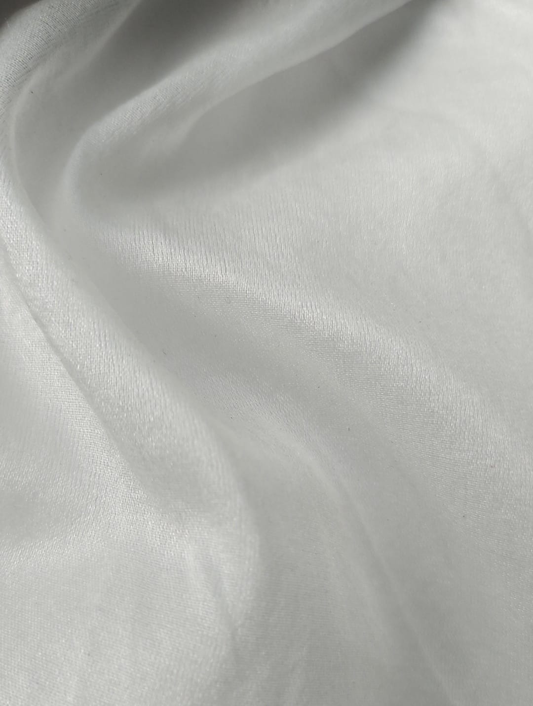 Close-up of soft, wrinkled pink cotton fabric displaying fine weave texture.