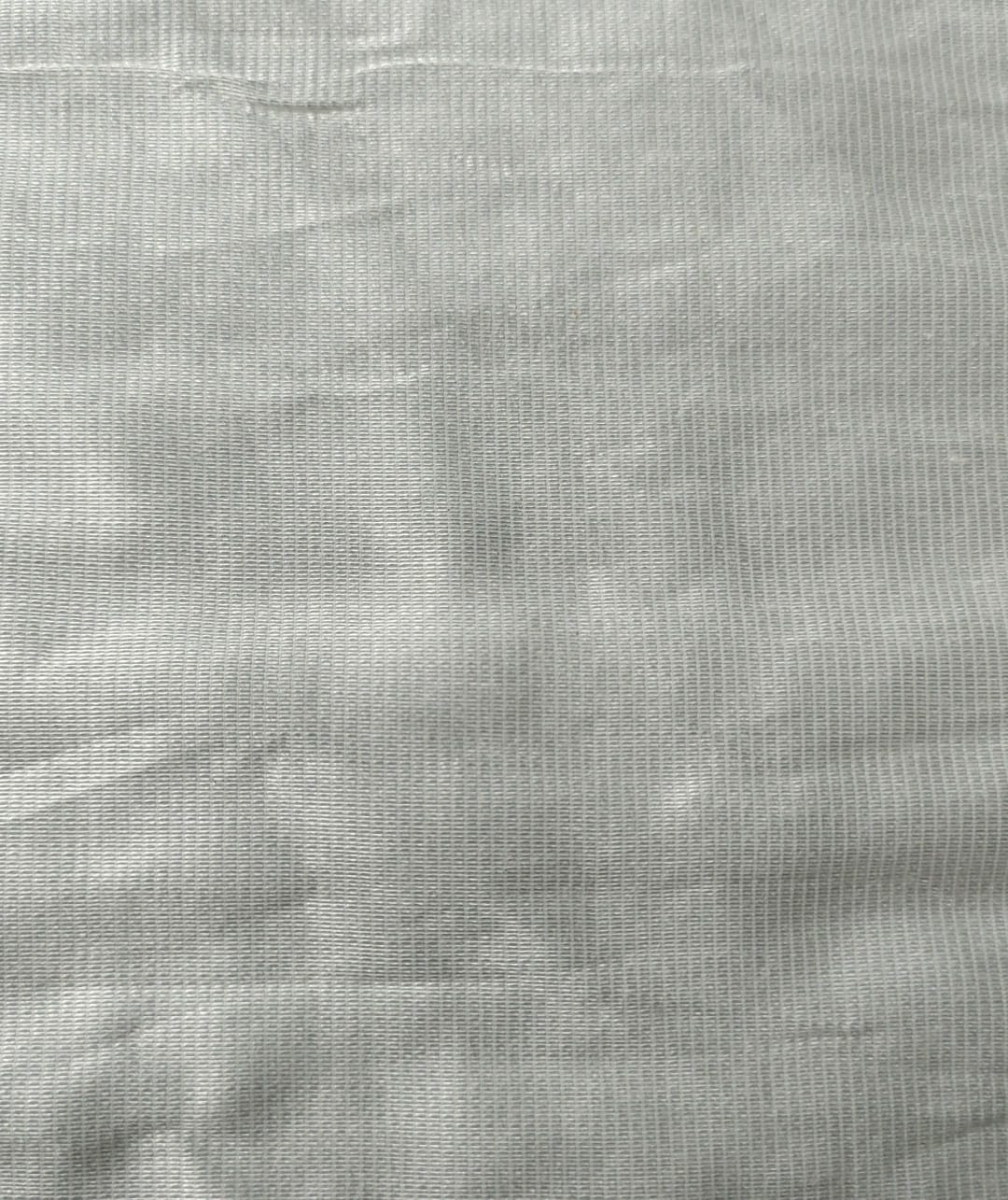 Close-up of soft, wrinkled pink cotton fabric displaying fine weave texture.