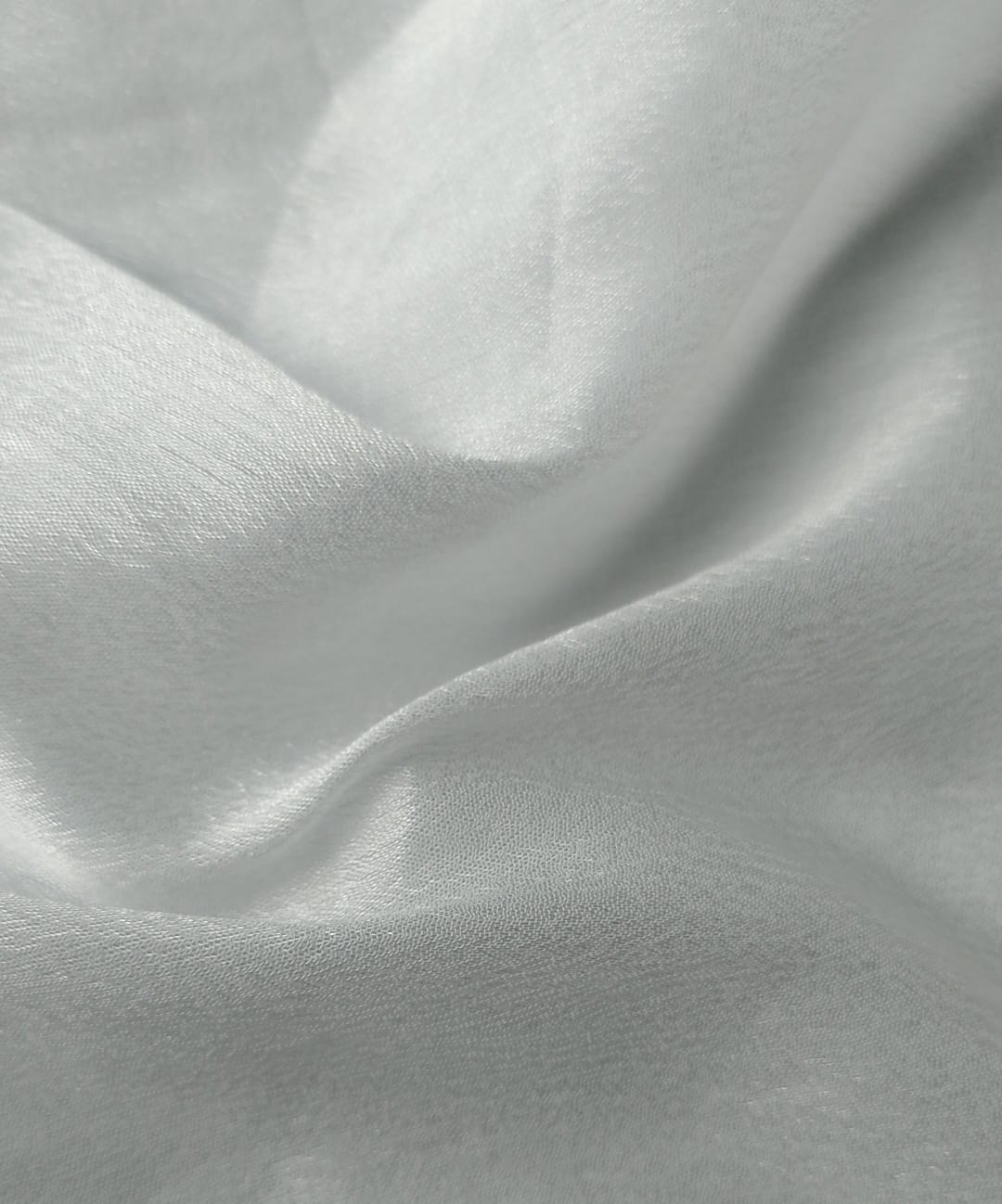 Close-up of soft, wrinkled pink cotton fabric displaying fine weave texture.