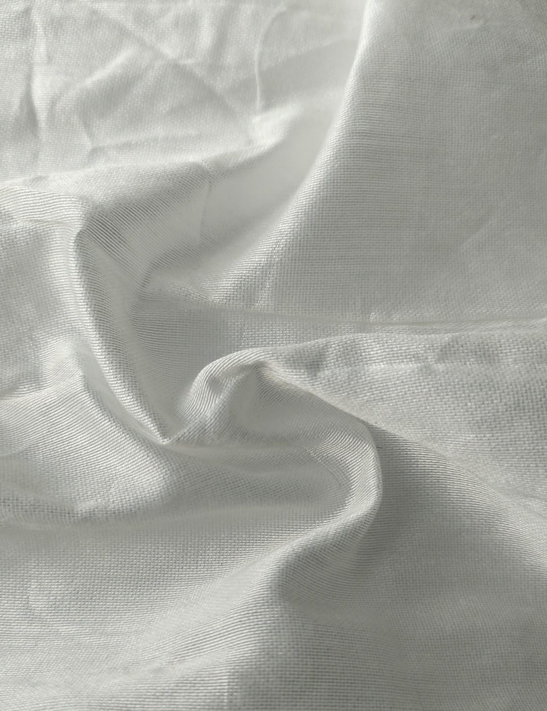 Close-up of soft, wrinkled pink cotton fabric displaying fine weave texture.