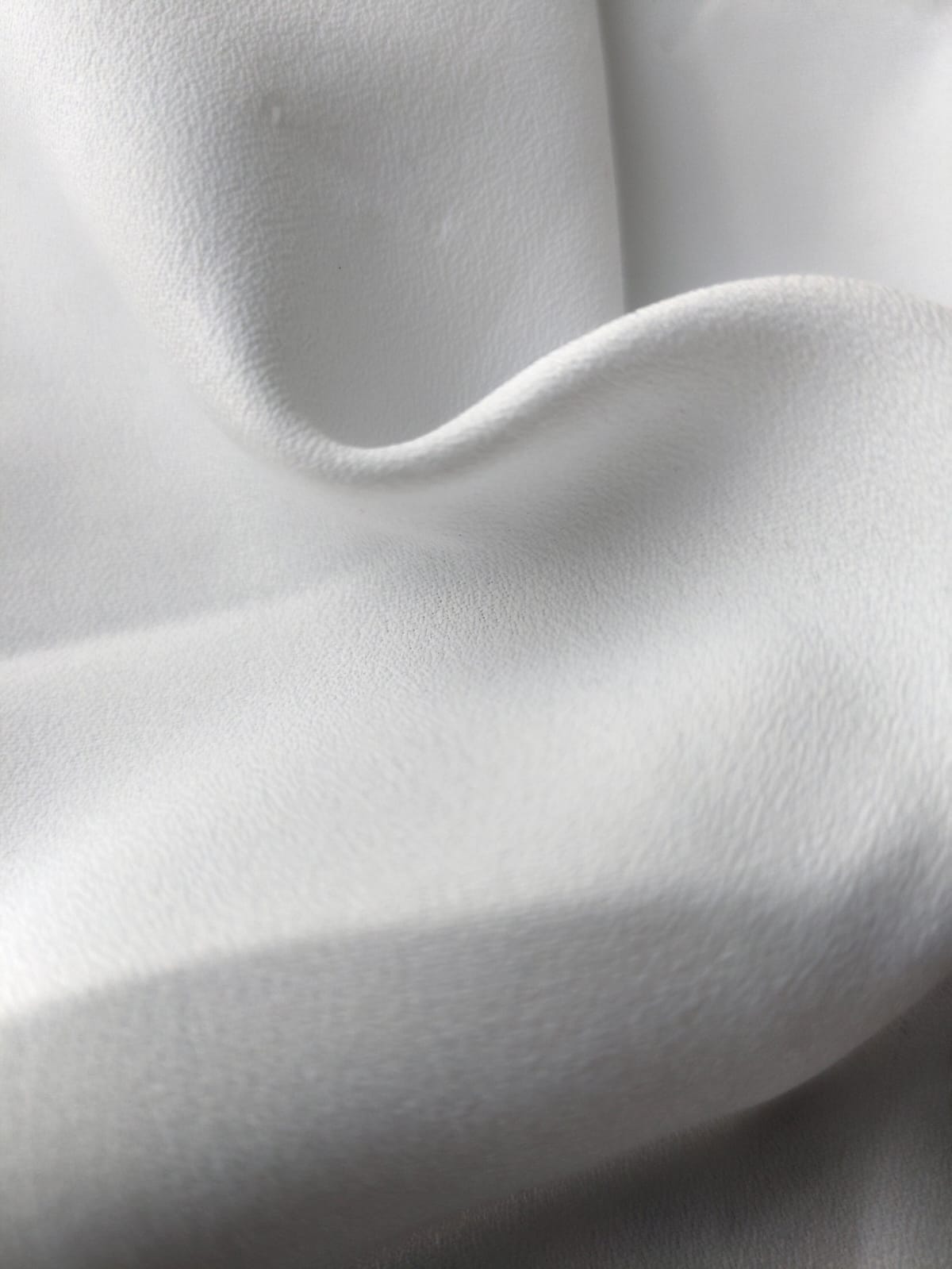 Close-up of soft, wrinkled pink cotton fabric displaying fine weave texture.