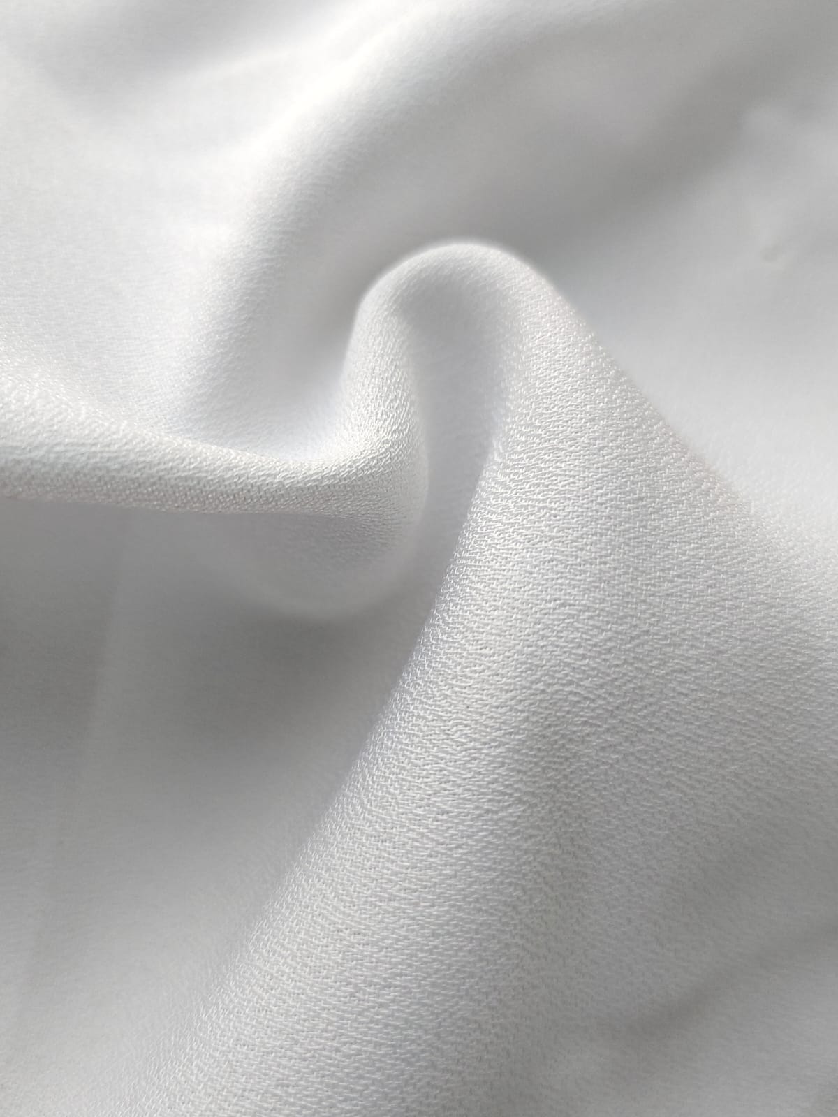 Close-up of soft, wrinkled pink cotton fabric displaying fine weave texture.