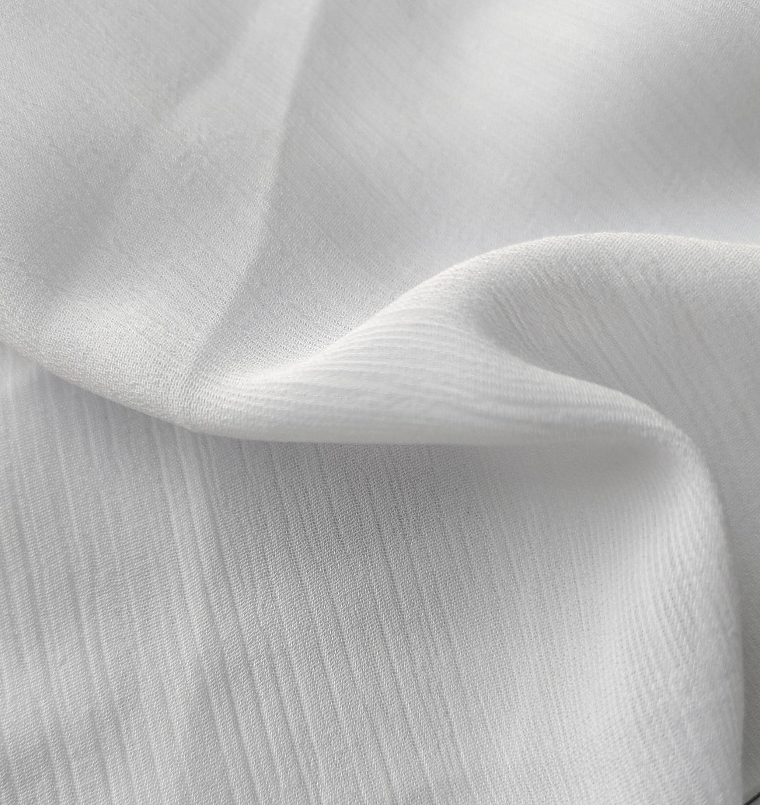 Close-up of soft, wrinkled pink cotton fabric displaying fine weave texture.
