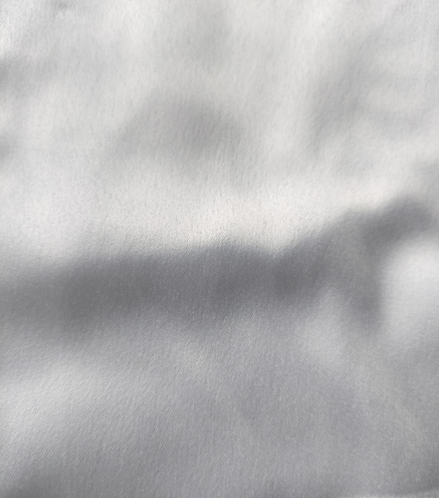 Close-up of soft, wrinkled pink cotton fabric displaying fine weave texture.