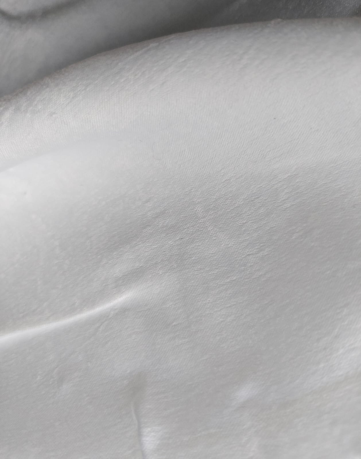 Close-up of soft, wrinkled pink cotton fabric displaying fine weave texture.