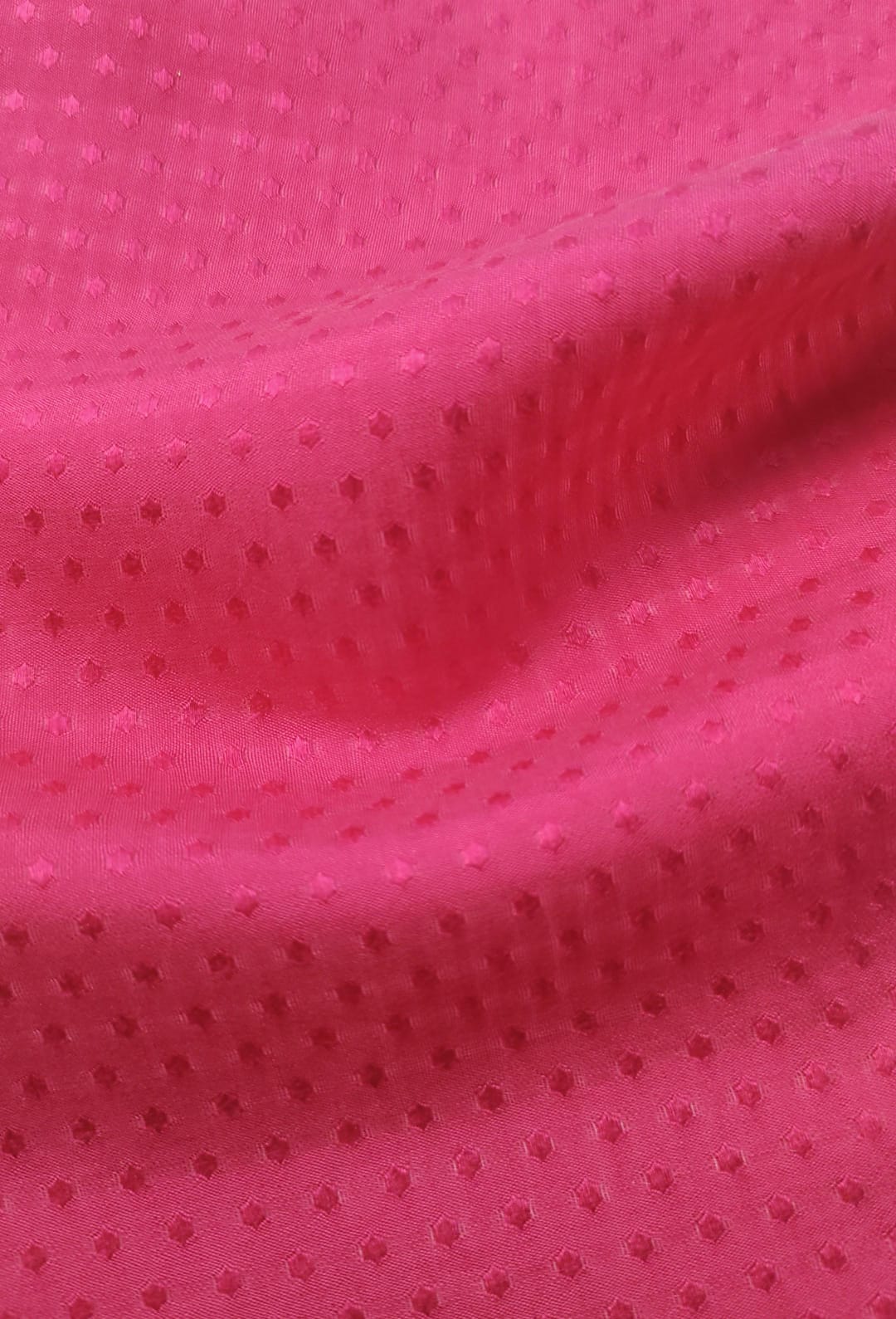 Close-up of soft, wrinkled pink cotton fabric displaying fine weave texture.