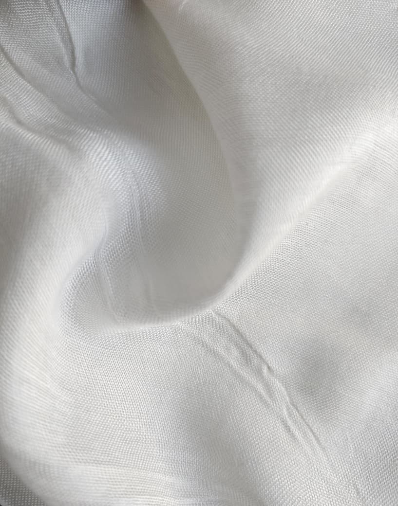 Close-up of soft, wrinkled pink cotton fabric displaying fine weave texture.