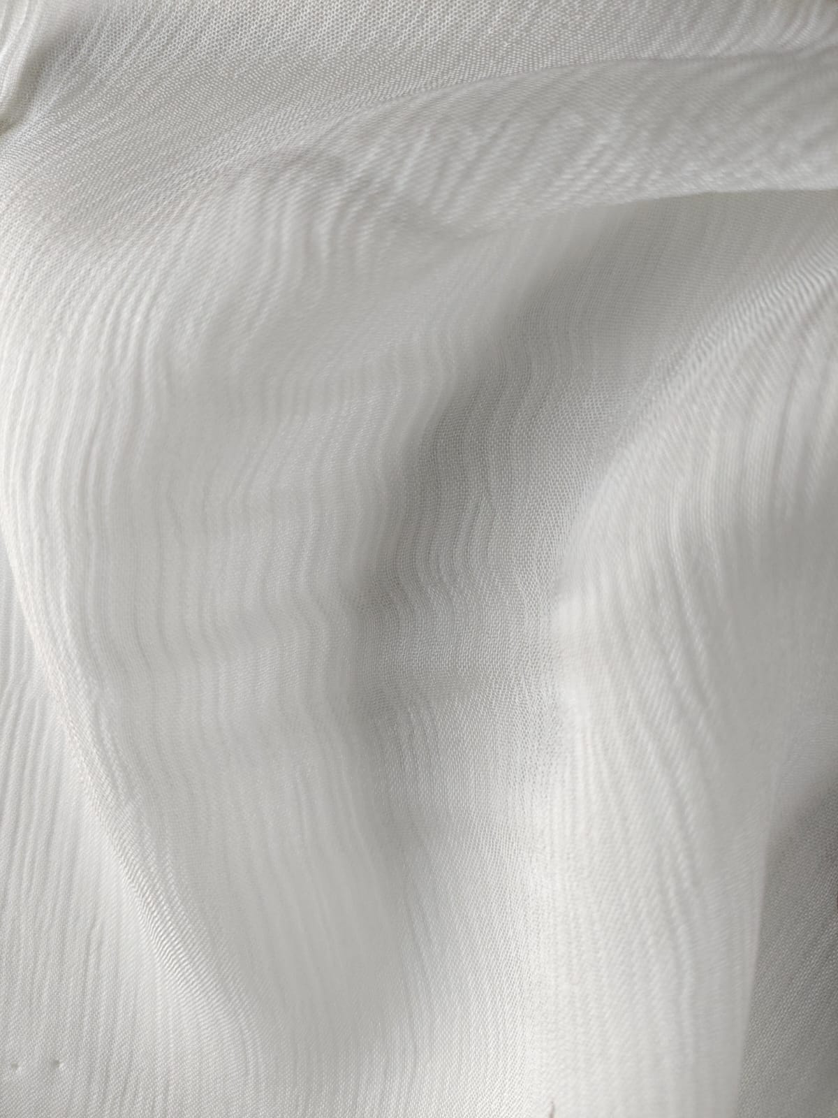 Close-up of soft, wrinkled pink cotton fabric displaying fine weave texture.
