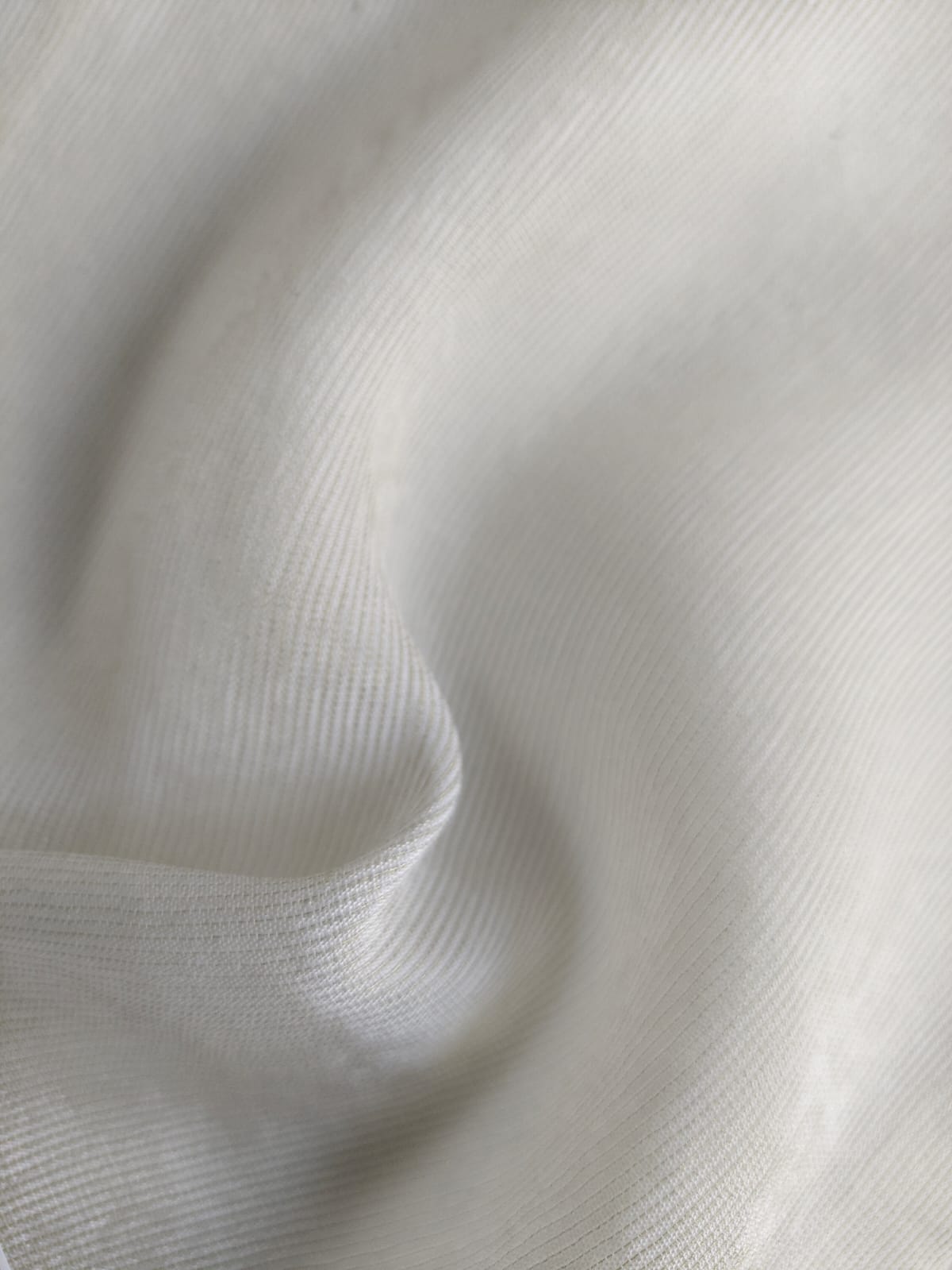 Close-up of soft, wrinkled pink cotton fabric displaying fine weave texture.