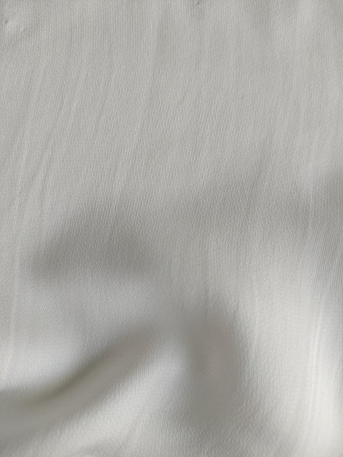 Close-up of soft, wrinkled pink cotton fabric displaying fine weave texture.