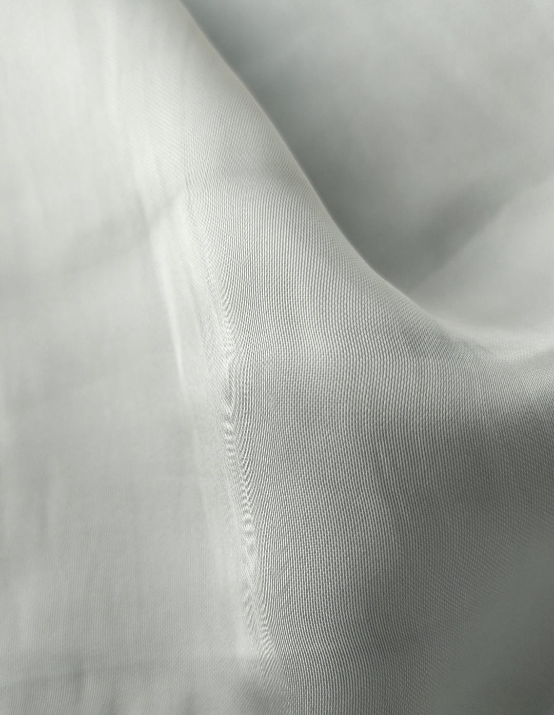Close-up of soft, wrinkled pink cotton fabric displaying fine weave texture.