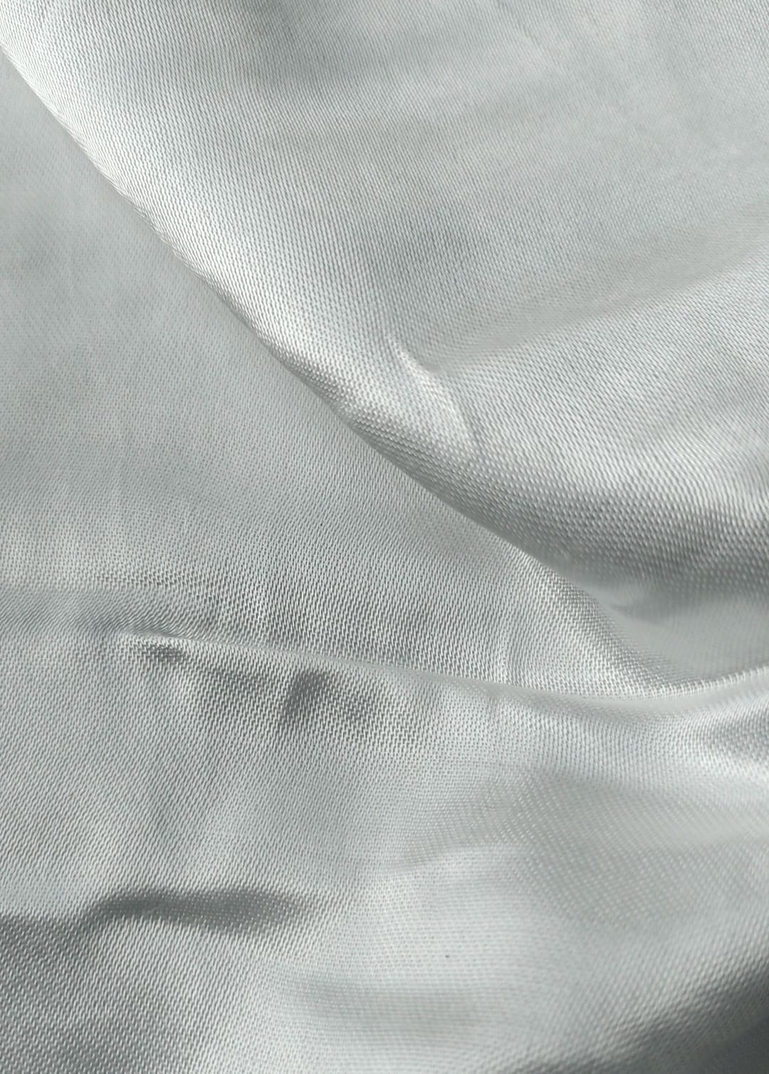 Close-up of soft, wrinkled pink cotton fabric displaying fine weave texture.
