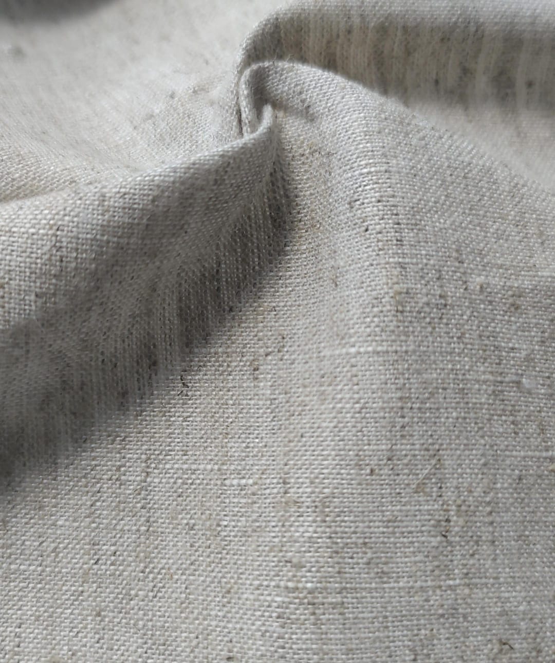 Close-up of soft, wrinkled pink cotton fabric displaying fine weave texture.
