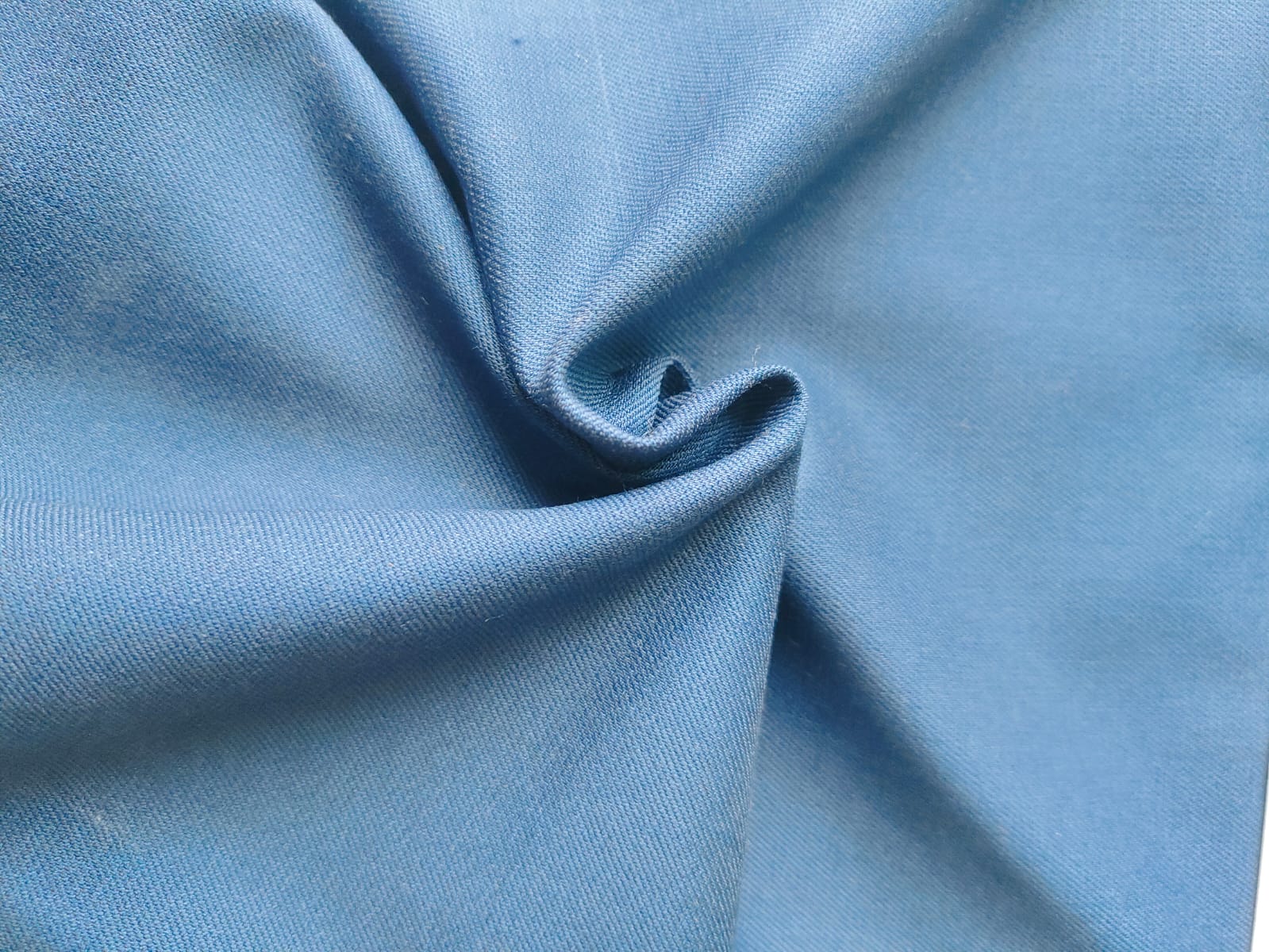 Close-up of soft, wrinkled pink cotton fabric displaying fine weave texture.