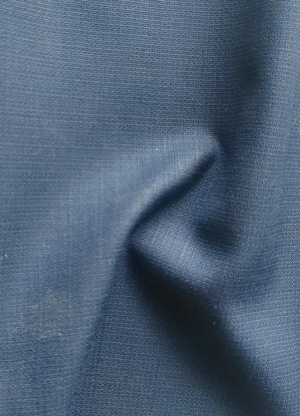 Close-up of soft, wrinkled pink cotton fabric displaying fine weave texture.