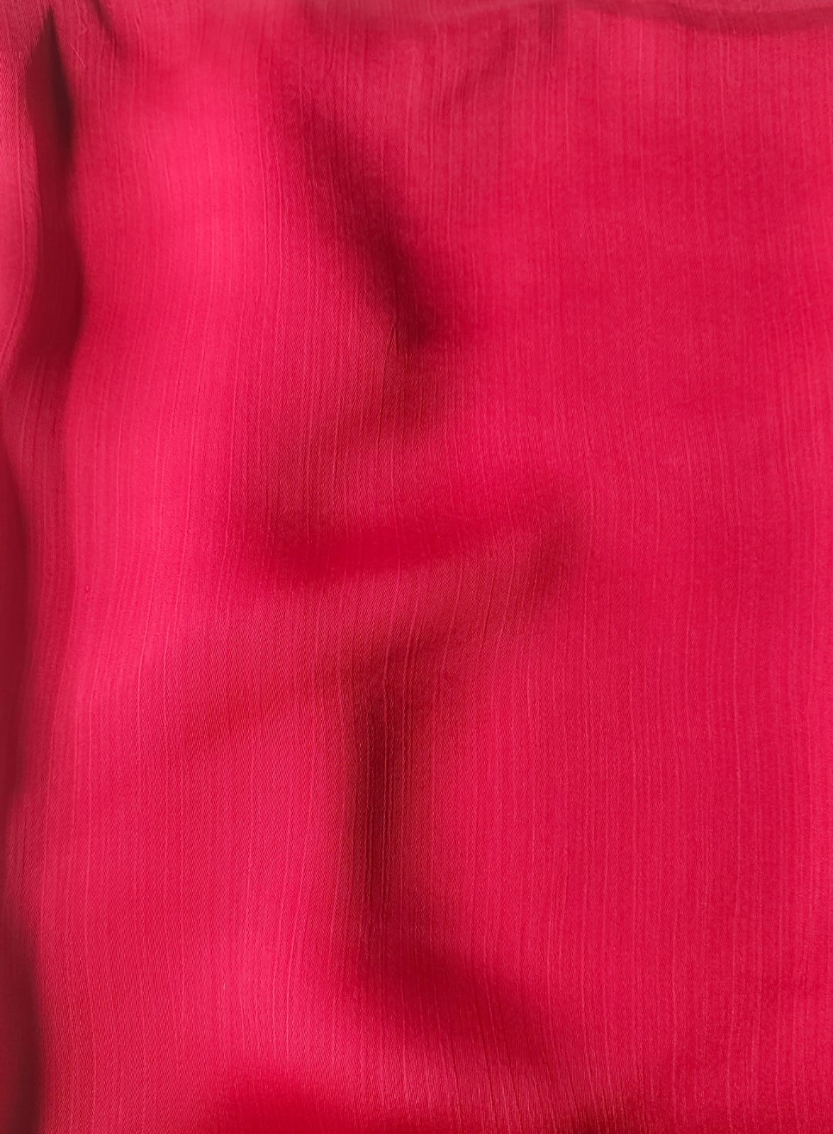 Close-up of soft, wrinkled pink cotton fabric displaying fine weave texture.