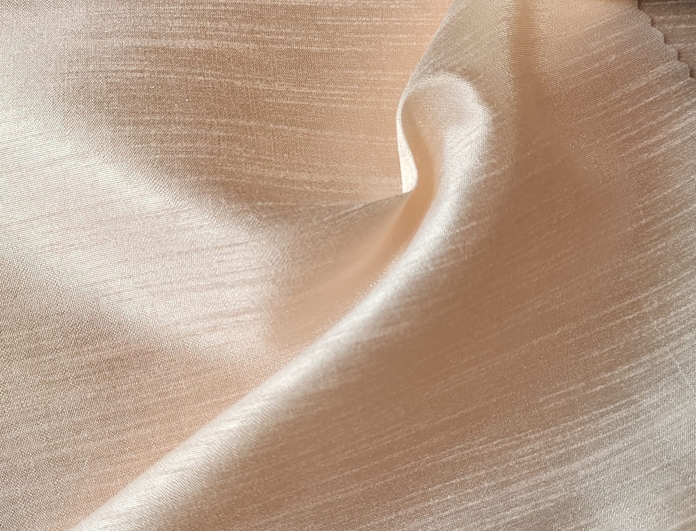Close-up of soft, wrinkled pink cotton fabric displaying fine weave texture.