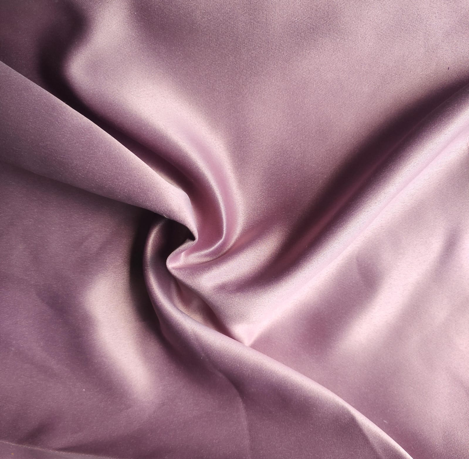 Close-up of soft, wrinkled pink cotton fabric displaying fine weave texture.