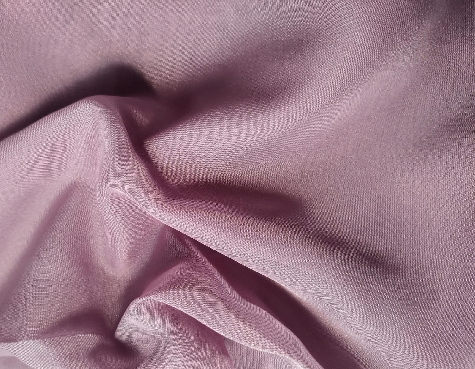 Close-up of soft, wrinkled pink cotton fabric displaying fine weave texture.