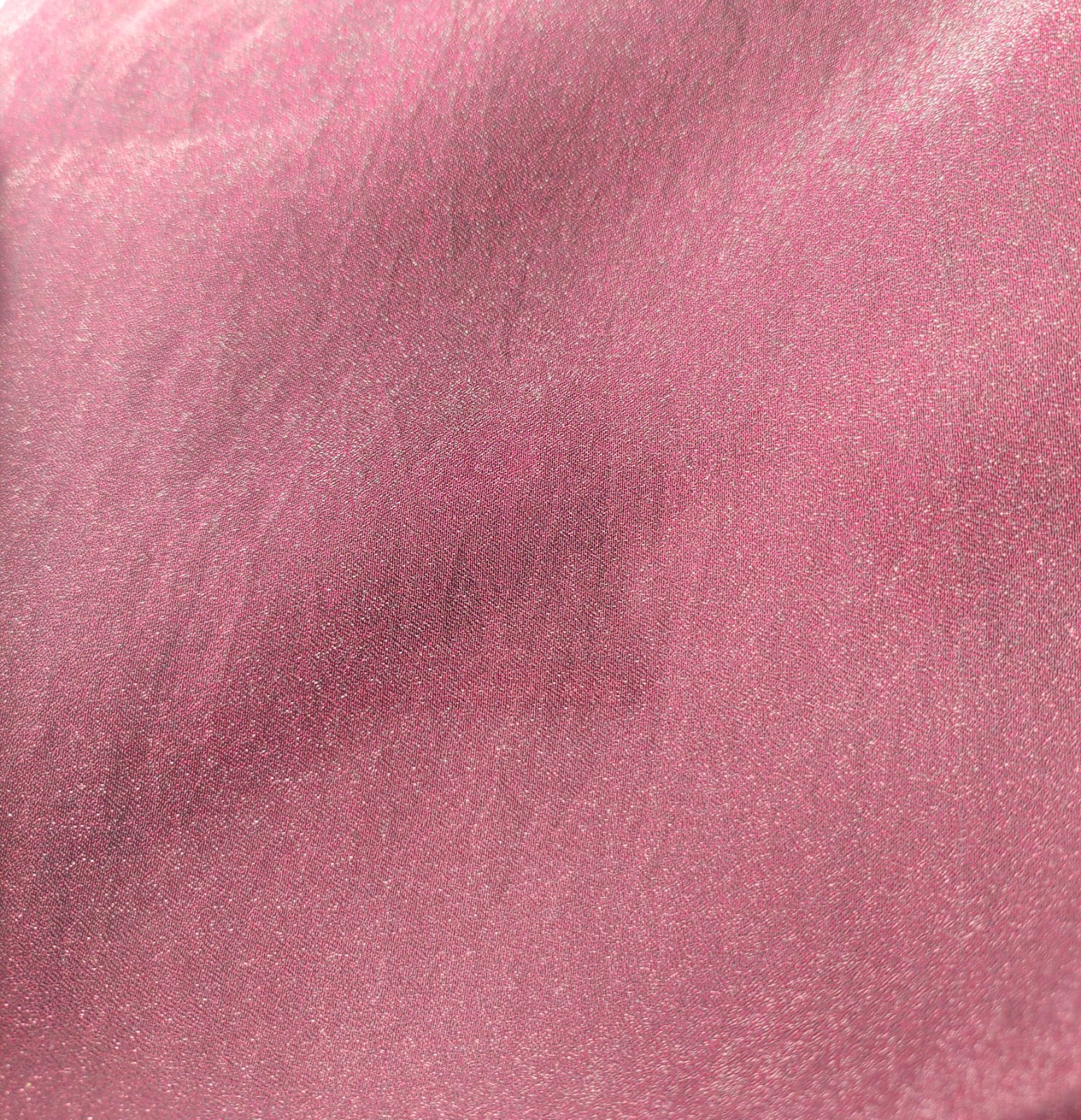 Close-up of soft, wrinkled pink cotton fabric displaying fine weave texture.