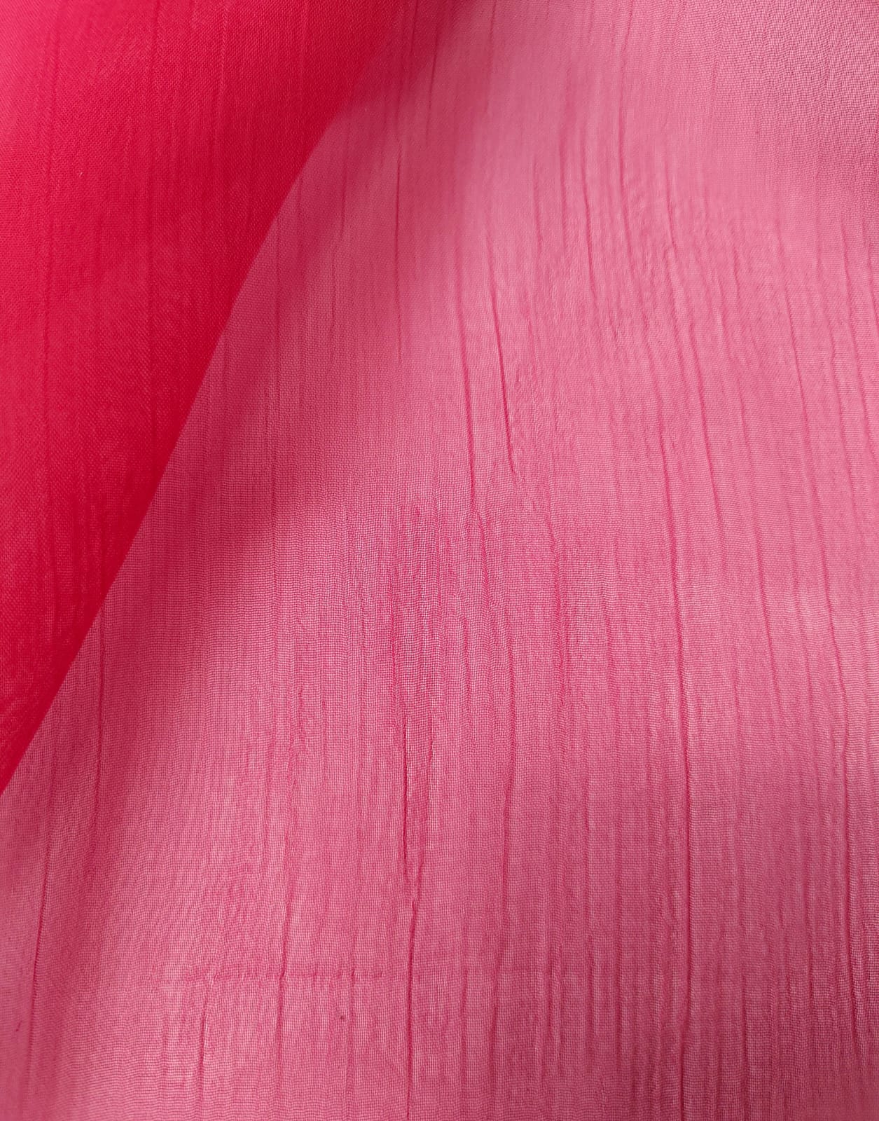 Close-up of soft, wrinkled pink cotton fabric displaying fine weave texture.