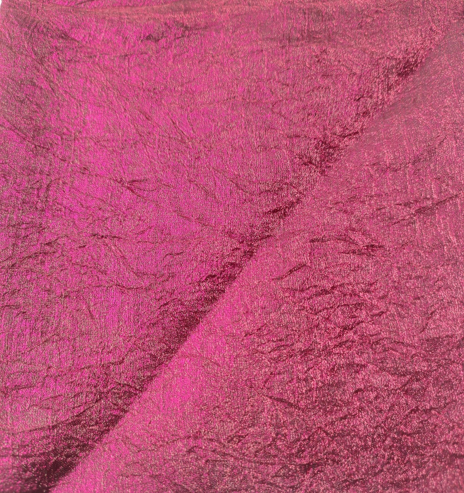 Close-up of soft, wrinkled pink cotton fabric displaying fine weave texture.