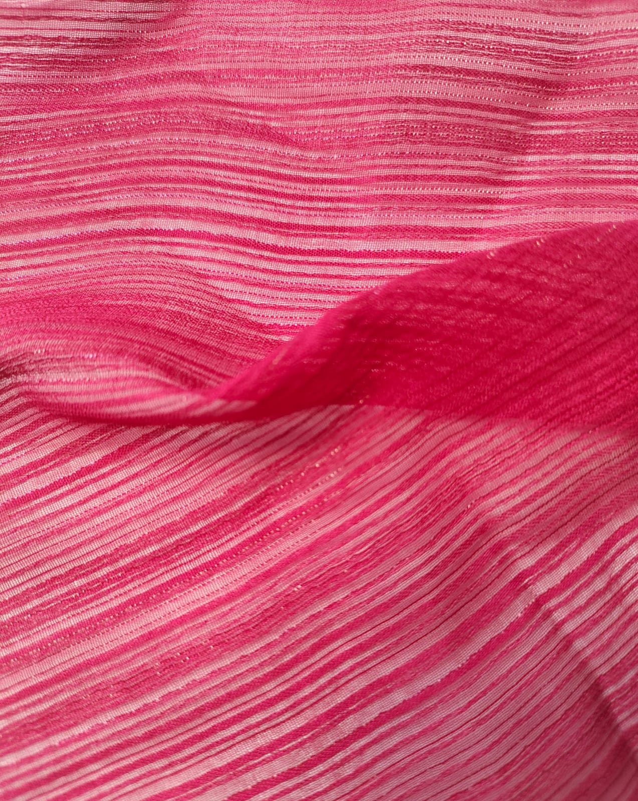 Close-up of soft, wrinkled pink cotton fabric displaying fine weave texture.