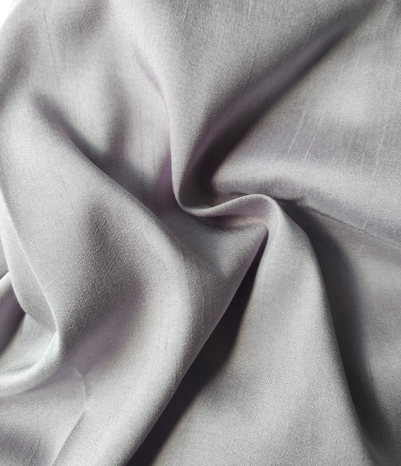 Close-up of soft, wrinkled pink cotton fabric displaying fine weave texture.