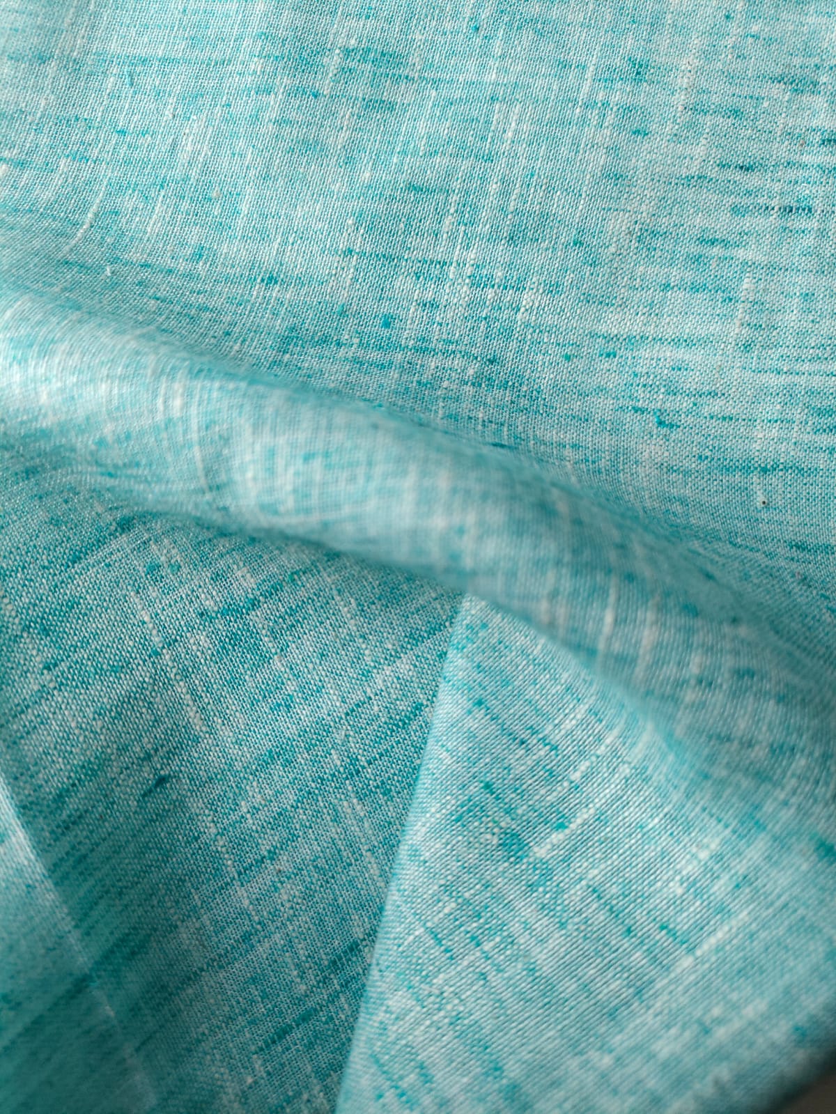 Close-up of soft, wrinkled pink cotton fabric displaying fine weave texture.