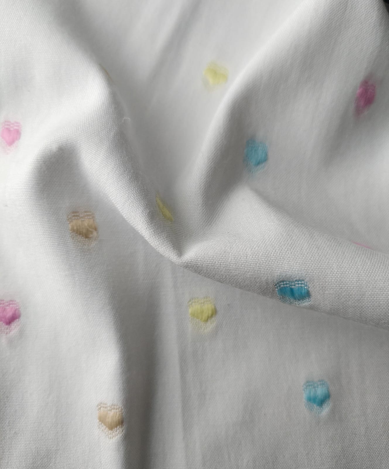 Close-up of soft, wrinkled pink cotton fabric displaying fine weave texture.