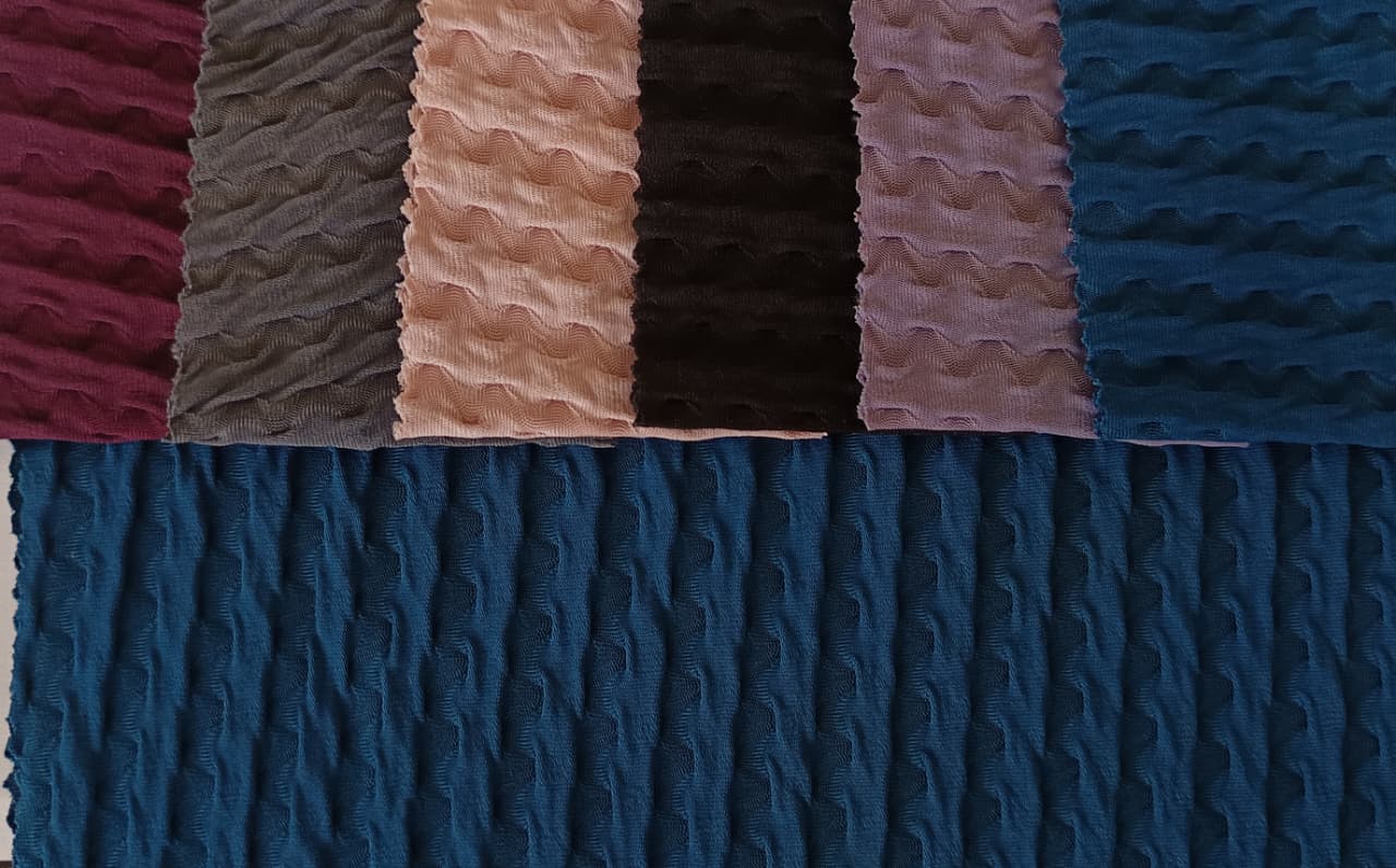 Close-up of soft, wrinkled pink cotton fabric displaying fine weave texture.