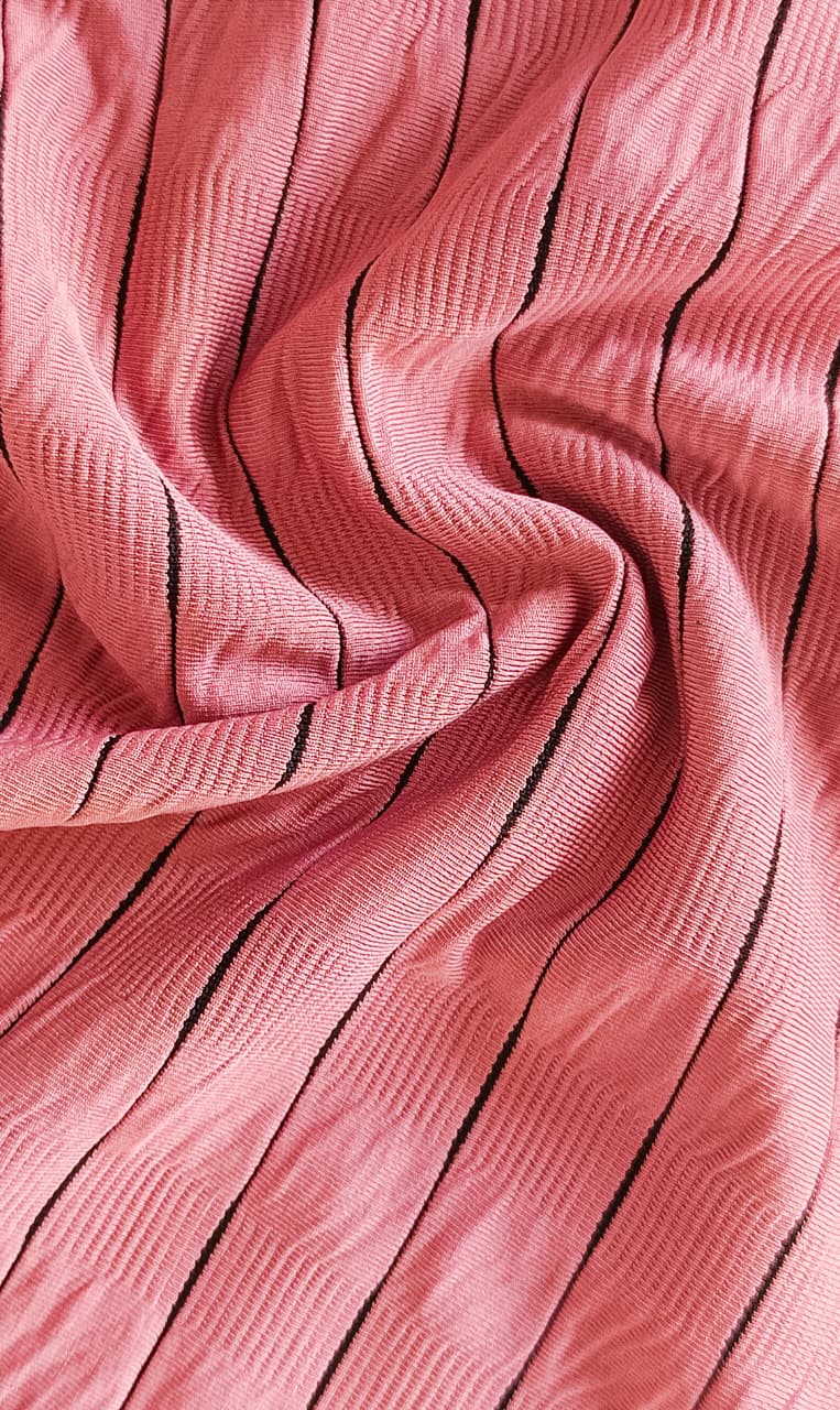 Close-up of soft, wrinkled pink cotton fabric displaying fine weave texture.